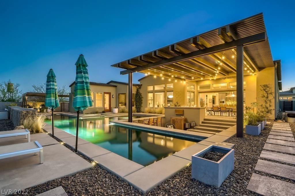 A blue-green geometric pool, sunken outdoor seating area and covered patio.